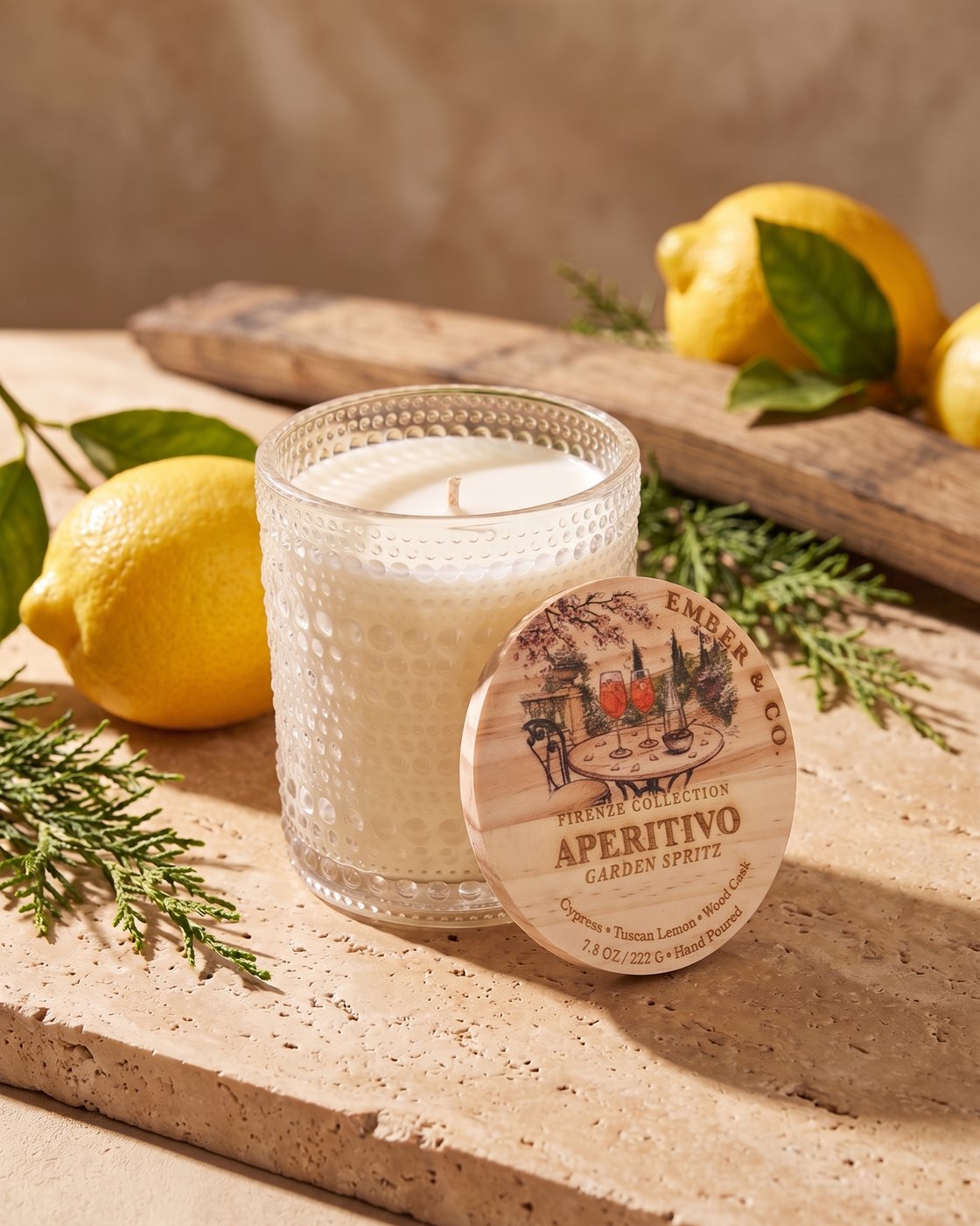 Aperitivo candle with its wooden lid, Tuscan lemons, cypress sprigs and an oak cask stave